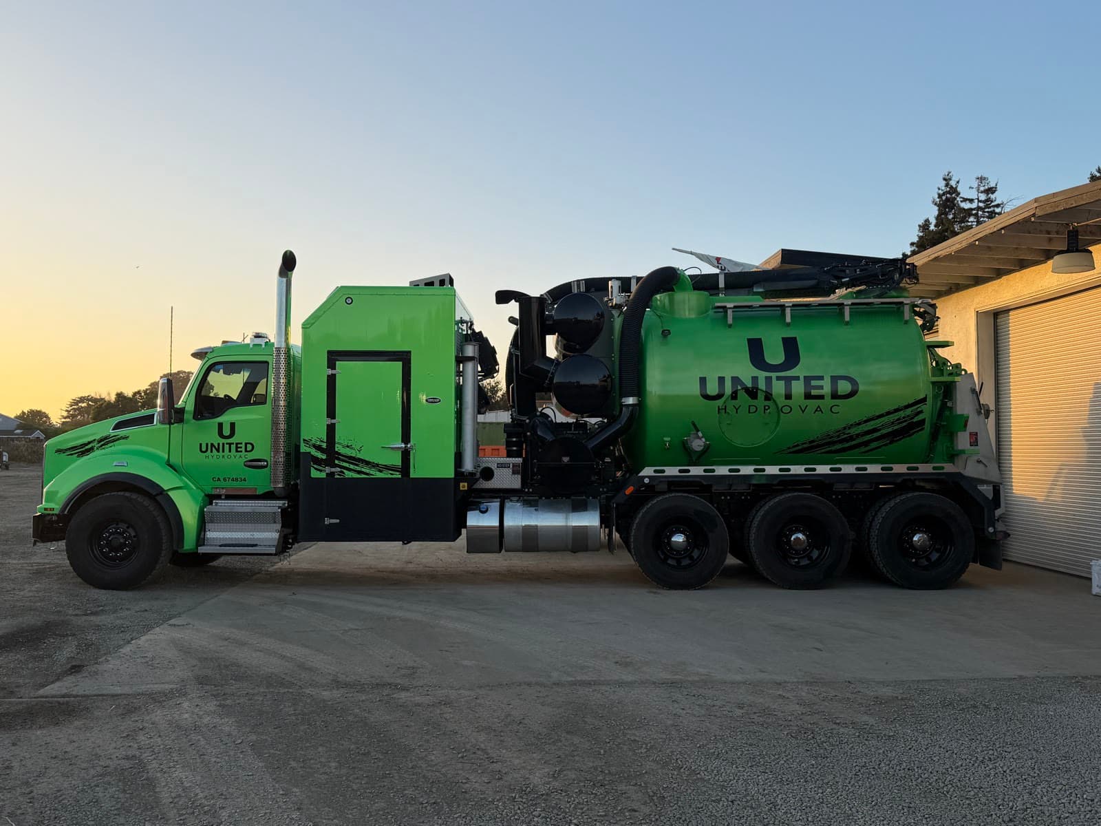 Green United Hydrovac vacuum excavation truck in side profile at dusk
